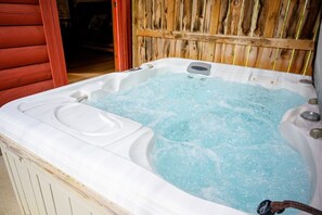 A hot tub with water, a wooden fence, and a red door.