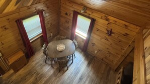 A wooden cabin with a round table and four chairs, two windows with blinds, and a star decoration on the wall. - Welcome to Fisherman's Dream, located near Hocking (McArthur)