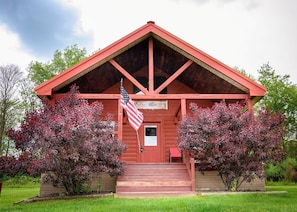 A wooden cabin with a red roof, a flag, and a welcome sign. - Welcome to Fisherman's Dream, located near Hocking (McArthur)