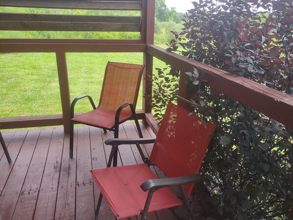 A wooden deck with two chairs and a red bag.