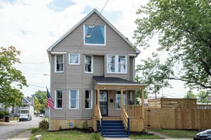 A two-story house with a front porch, a mailbox, and an American flag. - Modern Swanky Baseball Home, King Beds, Hot Tub, BBQ Grill, 5 min to Cle Clinic (Cleveland)