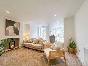 A living room with a sofa, armchairs, a fireplace, and a large abstract painting.