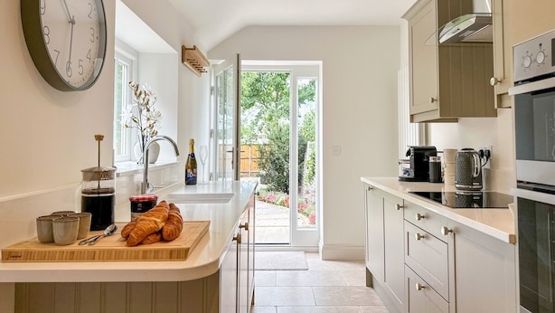 Een moderne keuken met een grote klok, een koffieapparaat en uitzicht naar buiten.