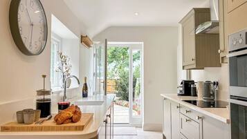 A modern kitchen with a large clock, a coffee machine, and a view to the outside.