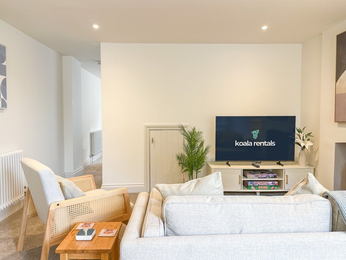 Un salon comprenant un canapé, deux fauteuils, une table basse, un téléviseur et une petite plante.