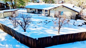 Un patio cubierto de nieve con una valla de madera, una casa y un garaje.