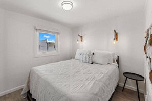 Bedroom with a comfy bed, bedside table, and wall sconces