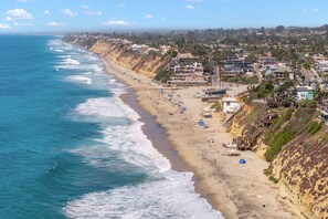 A coastal town with a beach, houses, and a clear view of the ocean.
