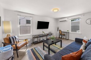 Living room with lots of seating, a wall-mounted TV, and A/C