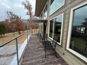 A covered outdoor deck with a railing, two chairs, and a table.