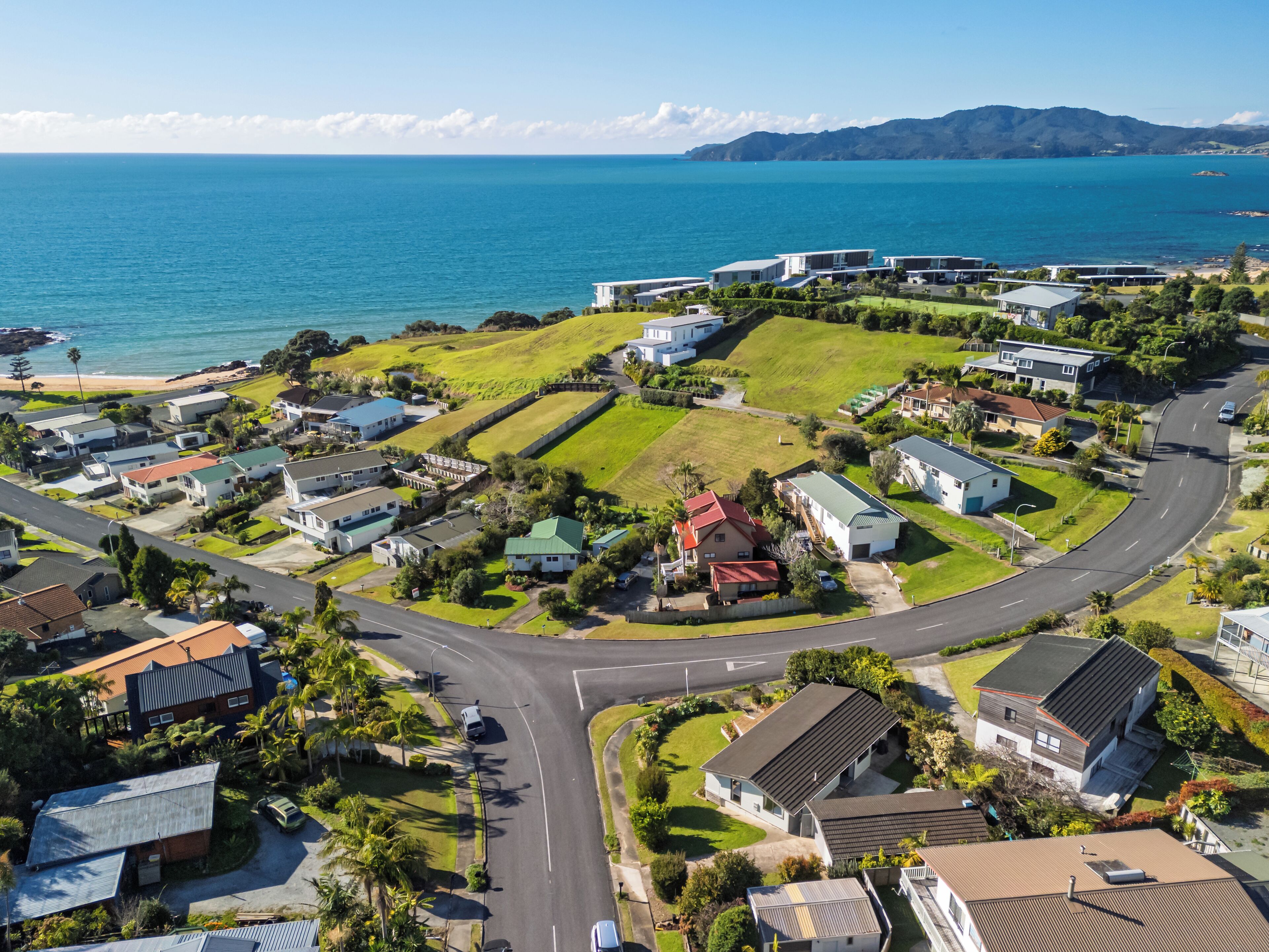 A coastal residential area with houses, roads, and a view of the sea.