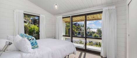 A bedroom with a large bed, a window with curtains, and a view of the outside.