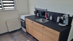 A modern kitchen with a black countertop, wooden cabinets, a stainless steel sink, and a built-in oven. - Cosy 2-bedroom apartment (Givet)