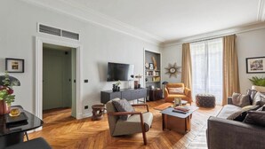 Ein modernes Wohnzimmer mit einer Couch, einem Sessel, einem Couchtisch und einem Fernseher auf einem Schrank.