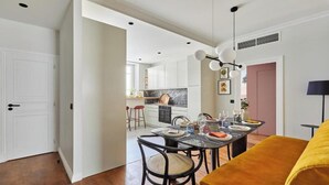 Eine moderne Küche mit weißen Schränken, einer Marmorarbeitsplatte und einem Essbereich mit einem gelben Sofa sowie einem Tisch für vier Personen.