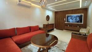 Una sala de estar moderna con un sofá modular, una mesa de centro, un televisor y un mueble de madera.