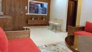 Una sala de estar moderna con un panel de pared de madera, un televisor montado, un sofá y una mesa de centro.