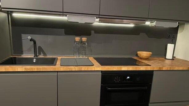 A modern kitchen with a wooden countertop, a built-in oven, and a sink with a faucet.