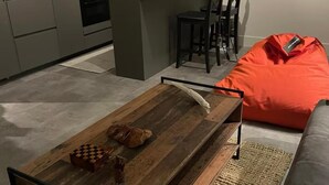 A living room with a wooden coffee table, a chessboard, and a plush orange bean bag.