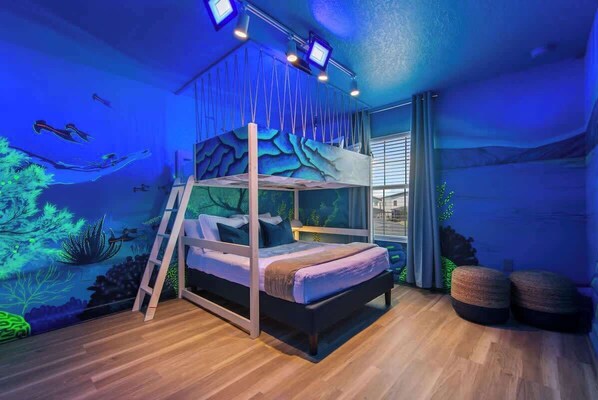 A bunk bed with a ladder, a window, and a wall mural.