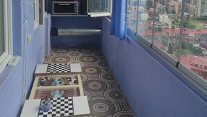 A narrow balcony with a checkered table, a fan, and a view of a cityscape with buildings and a construction site. - zura (Batumi)