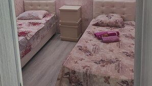 A bedroom with two beds, a nightstand, and a dresser. - zura (Batumi)