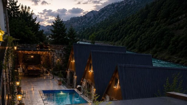 Ein Hotel mit Pool, Sitzgelegenheiten im Freien und Blick auf Berge.