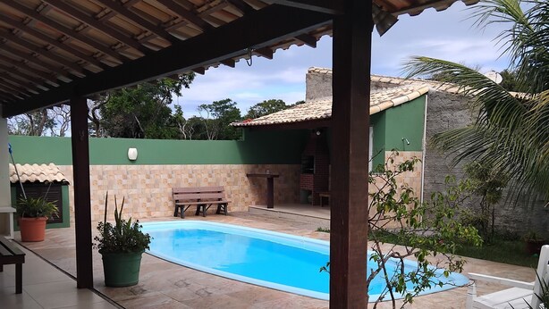 Un espacio exterior techado con piscina, una parrilla y una zona de estar.