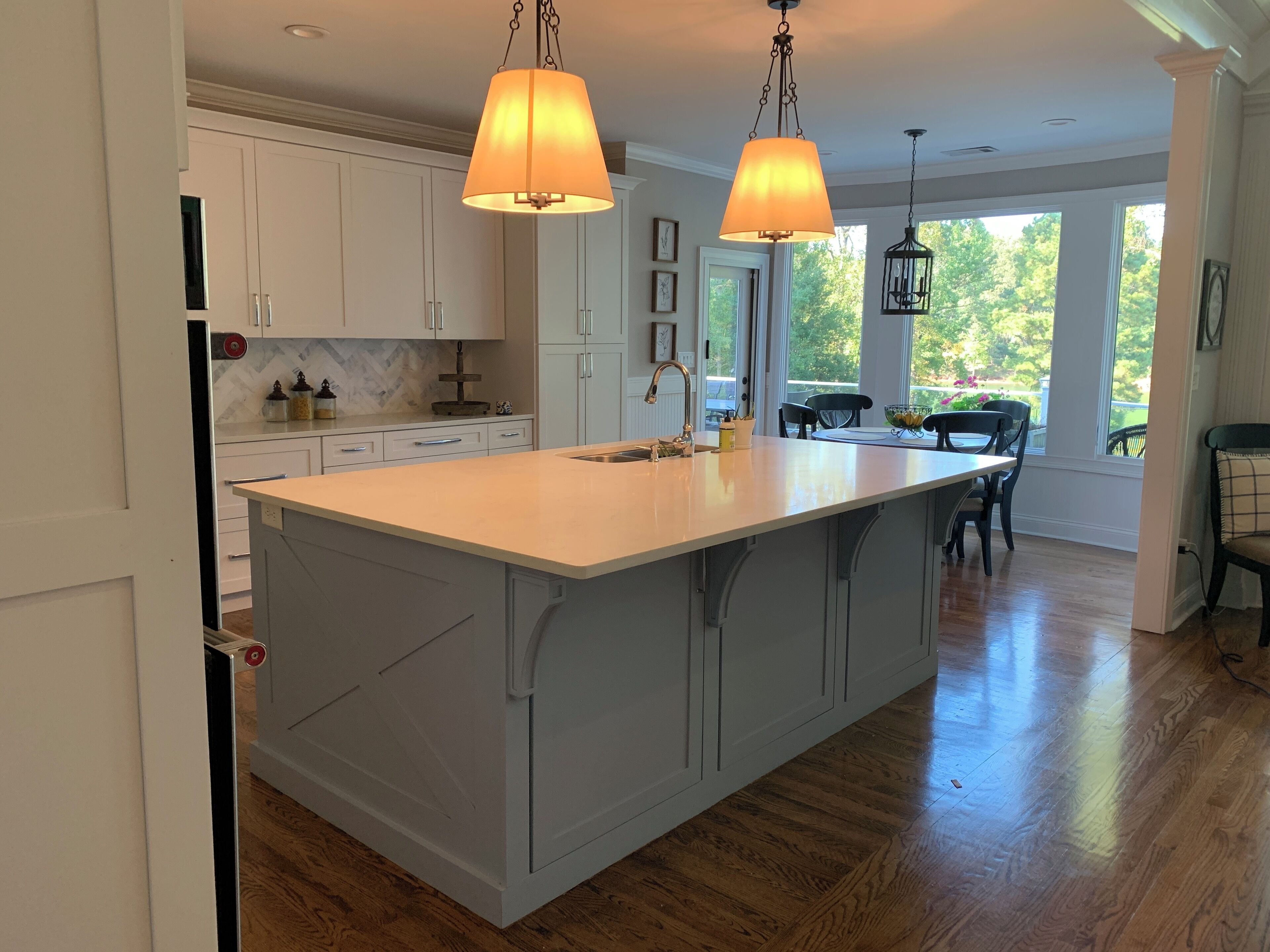 A spacious kitchen with a large island, pendant lighting, and a view to the outdoors.