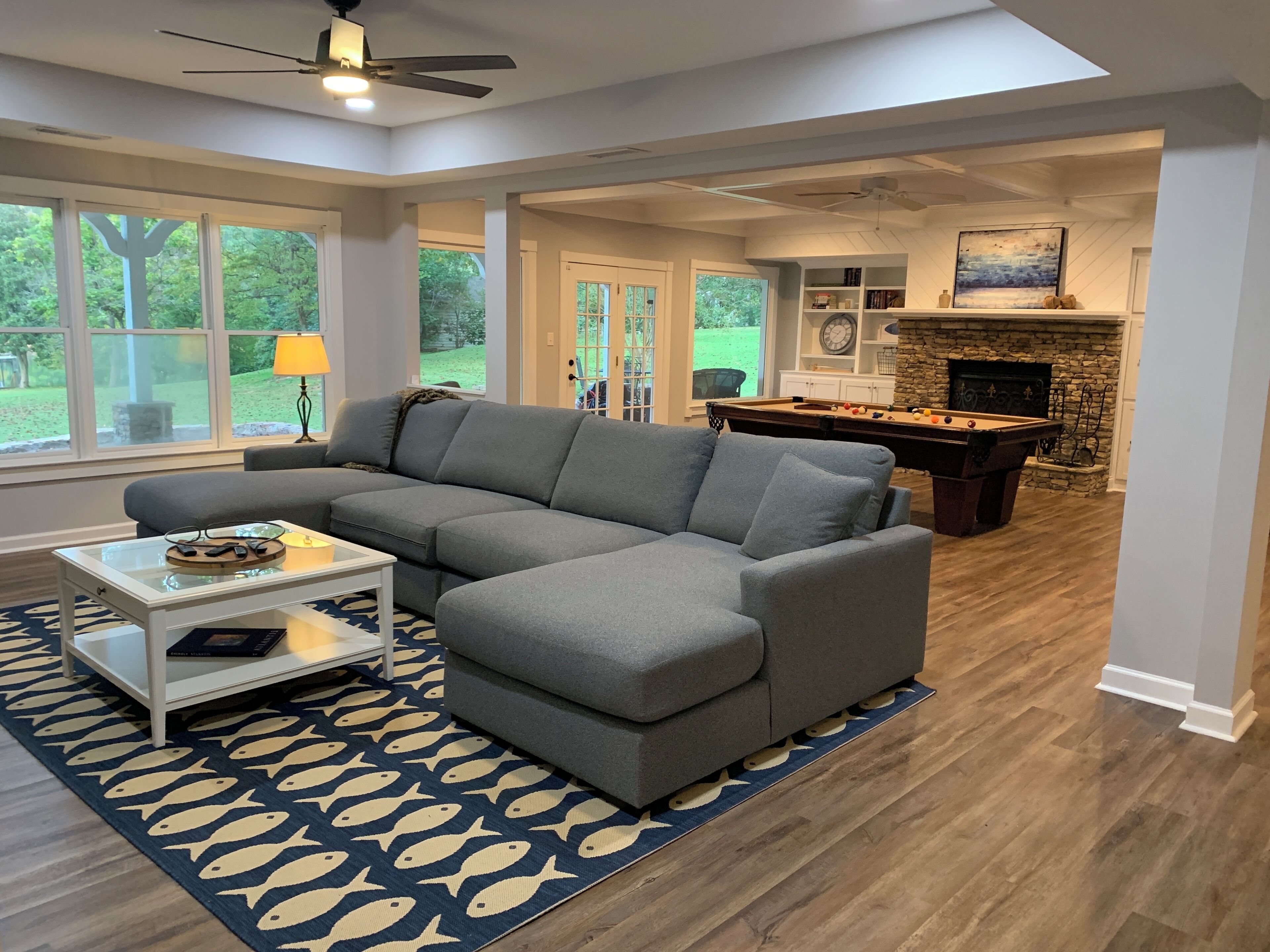 A living room with a sectional sofa, a pool table, and a fireplace.