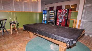 A room with a bed, a green wall, and vending machines.