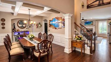 A dining area with a long wooden table, multiple chairs, and a chandelier.