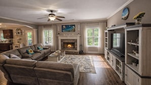 A living room with a fireplace, a sofa, a TV, and a ceiling fan.