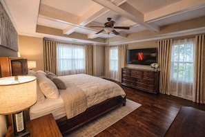 A bedroom with a bed, a dresser, a TV, and a ceiling fan.