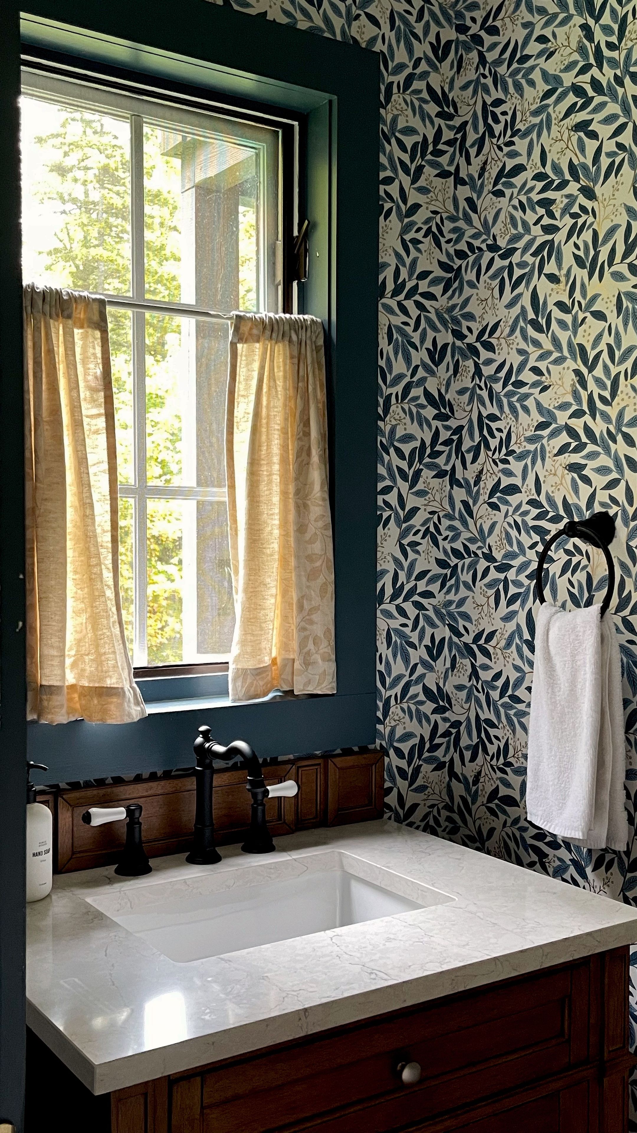 A bathroom with a window, a sink, and a towel rack.