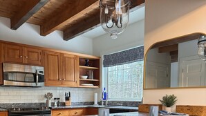 Una cocina con armarios de madera, un horno de acero inoxidable, un microondas y una isla grande con taburetes de bar.