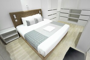 A neatly arranged bedroom with a bed, bedside tables, and built-in storage units.