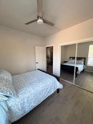 A bedroom with a bed, a ceiling fan, a wardrobe, and a mirror.