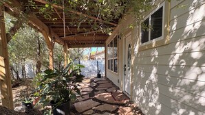 A covered patio with stone flooring, potted plants, and a wooden pergola. - Cozy Casita in San Antonio Close to sea world- downtown-fiesta Texas-Alamo ranch (San Antonio)