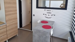 Une chambre moderne avec une armoire en bois, une table à manger agrémentée de sets de table rouges, un miroir mural et une citation décorative sur le mur.
