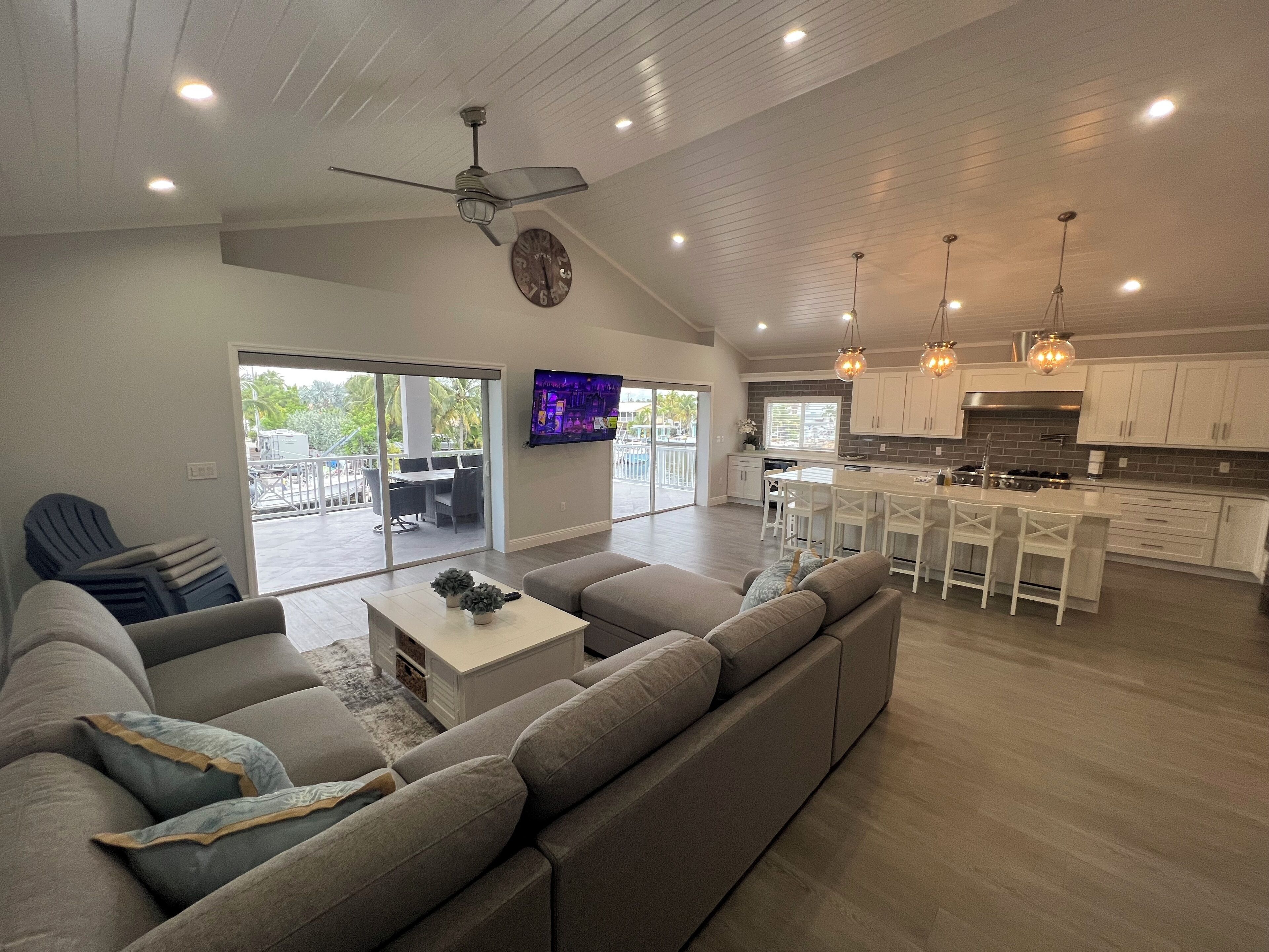 A spacious living area with a large sofa, a coffee table, and a television mounted on the wall.