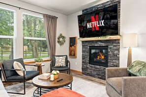 Un soggiorno con camino, il logo di Netflix, un muro in pietra e un'ampia finestra con persiane.
