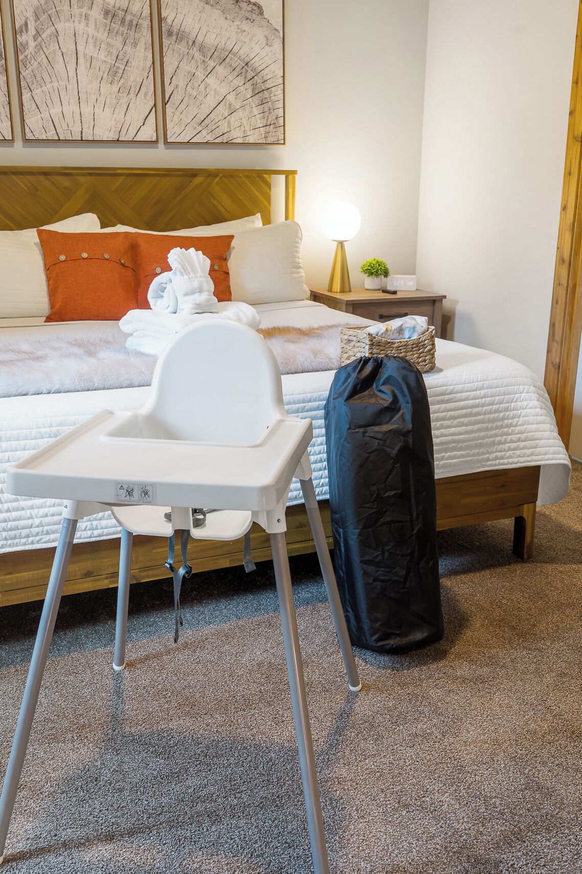 Una habitación de hotel con una cama, una mesita de noche con lámpara, una silla y una maleta.