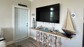 Un salón con una mesa consola de madera, un televisor montado y una decoración con un velero.