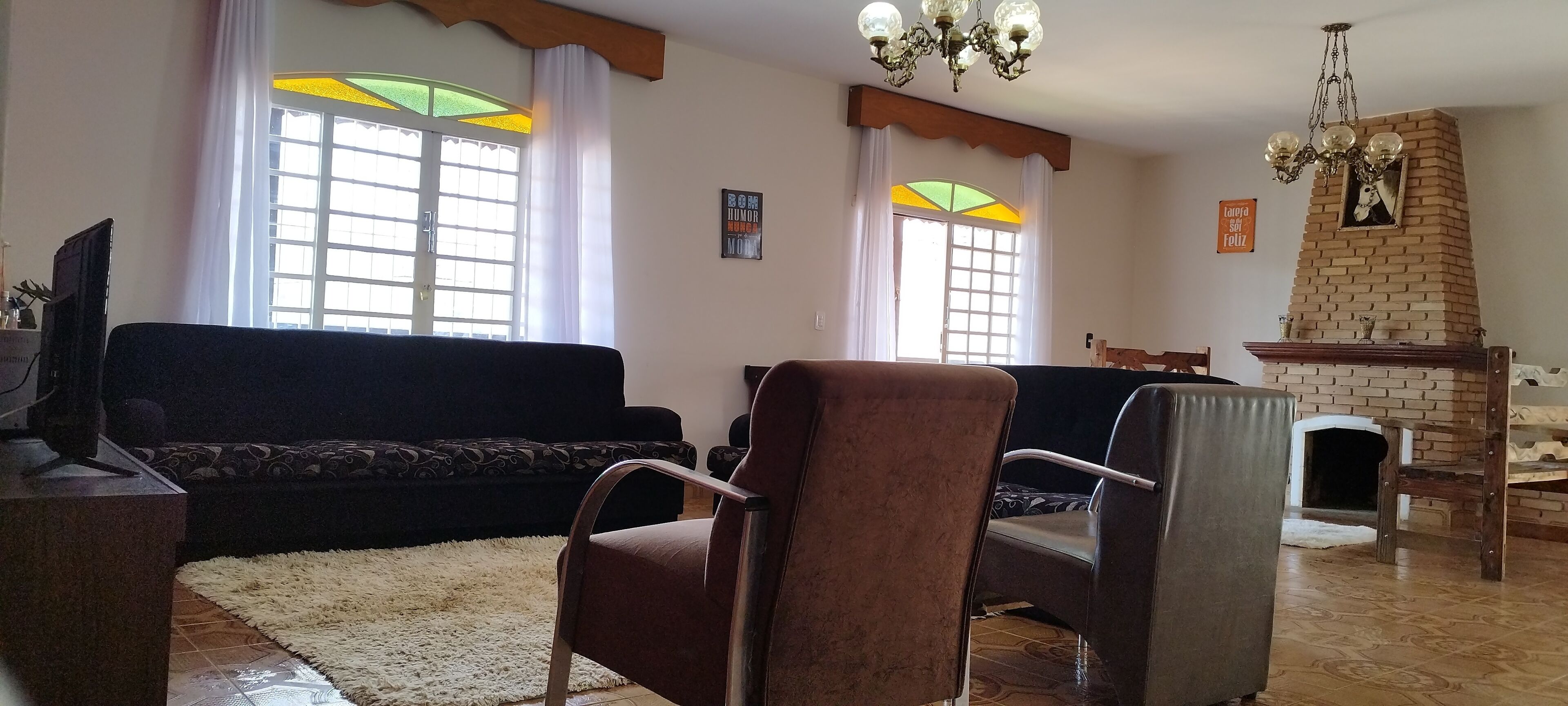 Una sala de estar con un sofá, sillones, chimenea y televisor.