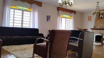 Una sala de estar con un sofá, sillones, chimenea y televisor.