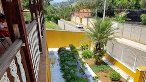Un patio con un camino empedrado, una pared amarilla y una barandilla blanca.