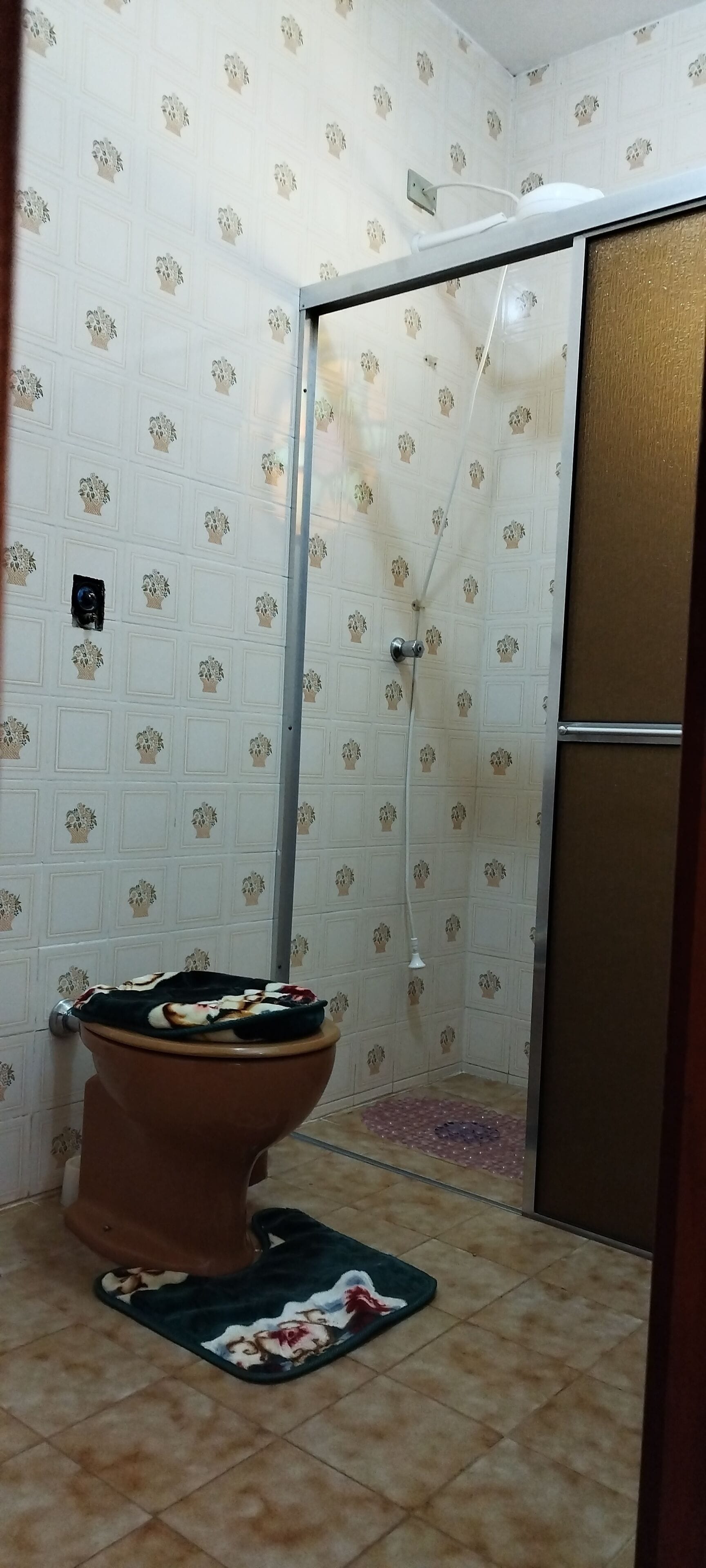 Un baño con inodoro, ducha y paredes de azulejos.
