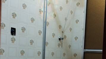 Un baño con inodoro, ducha y paredes de azulejos.