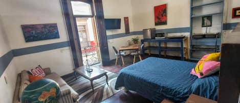 Un dormitorio con una cama, un escritorio, una silla, un acuario y una ventana.